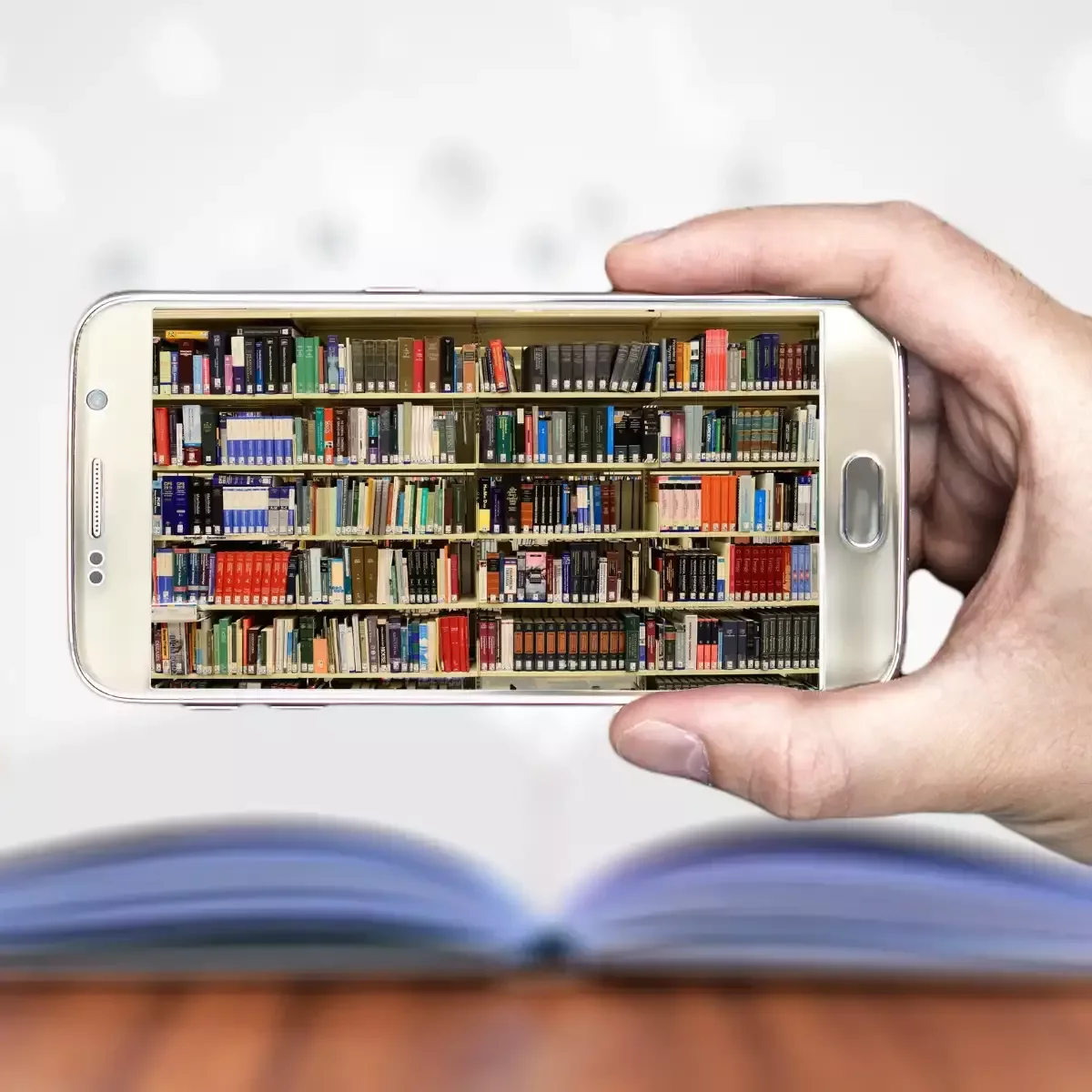 Offenes Buch liegt auf einem Schreibtisch neben einem Smartphone mit Social-Media-App – Symbol dafür, dass ein Buch mehr Wirkung und Nachhaltigkeit hat als 100 Posts.